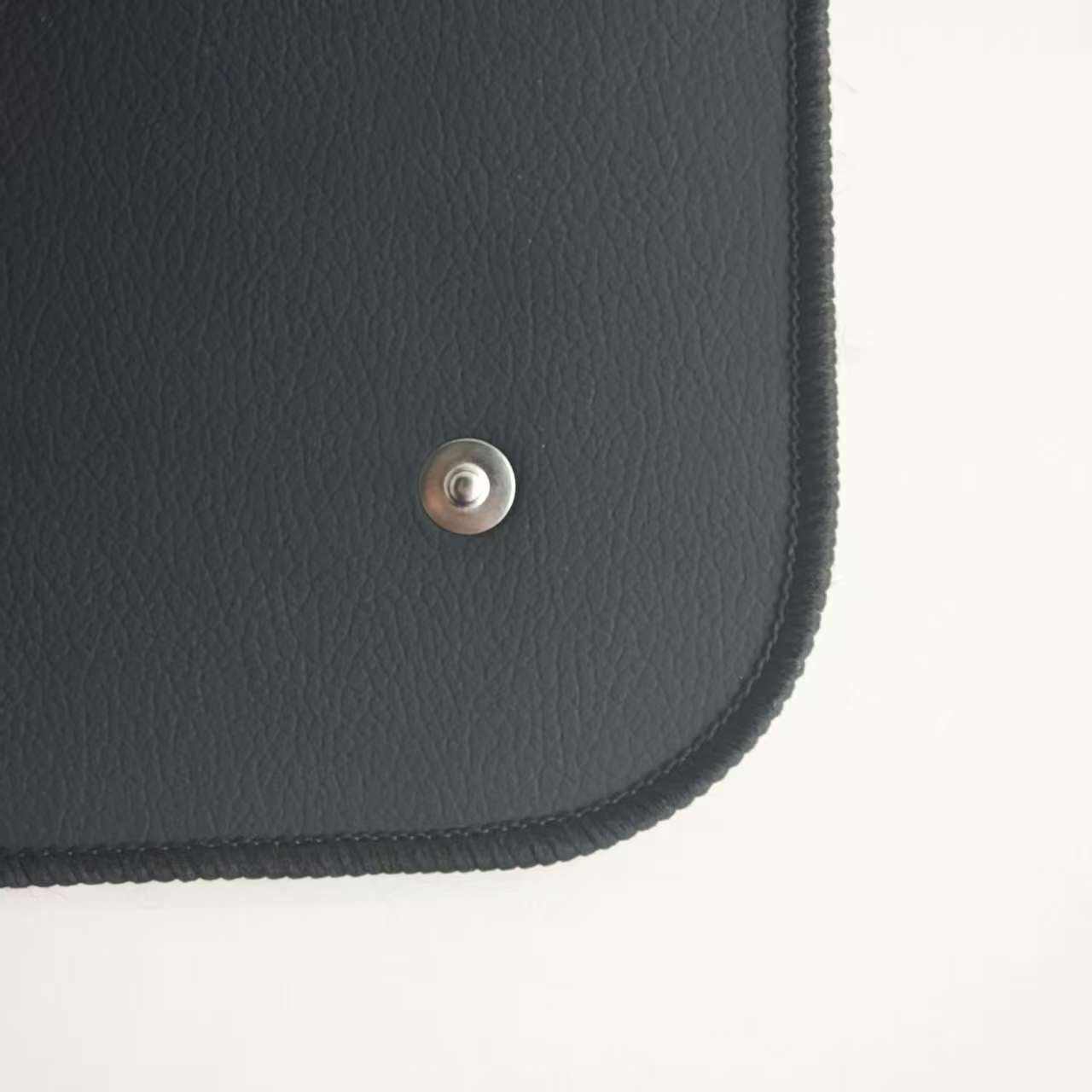 Close up view of the pebbled leather texture and metal connection button on a black grounding mat.