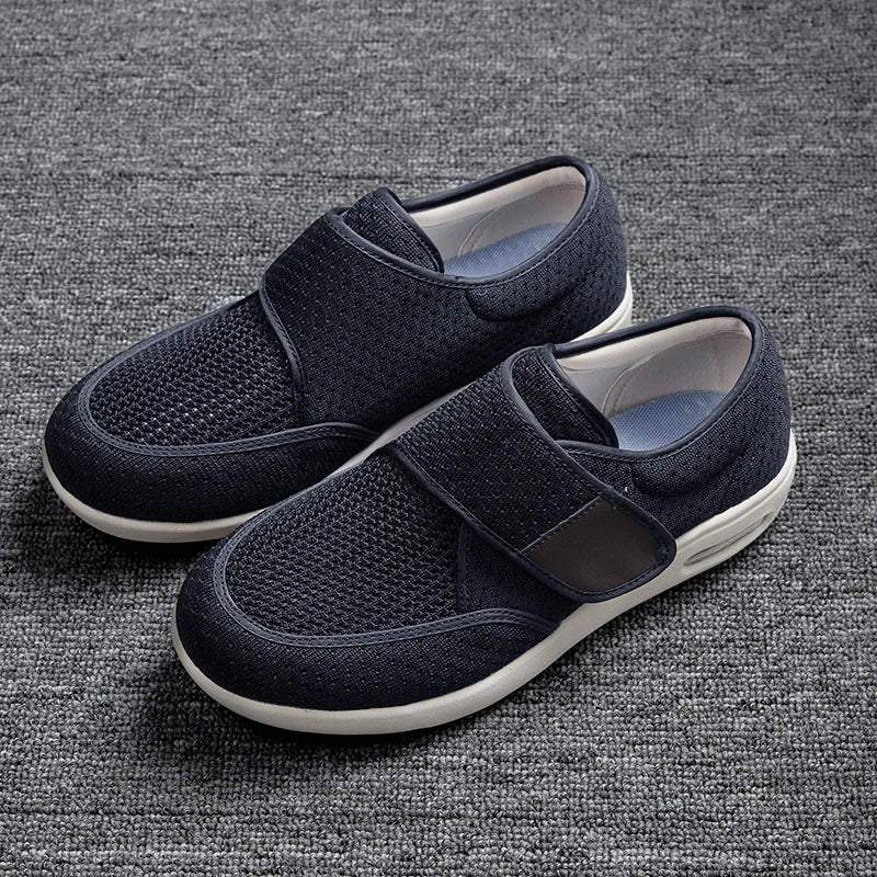 A pair of navy blue orthopedic shoes featuring a breathable mesh upper and velcro straps on a gray background.